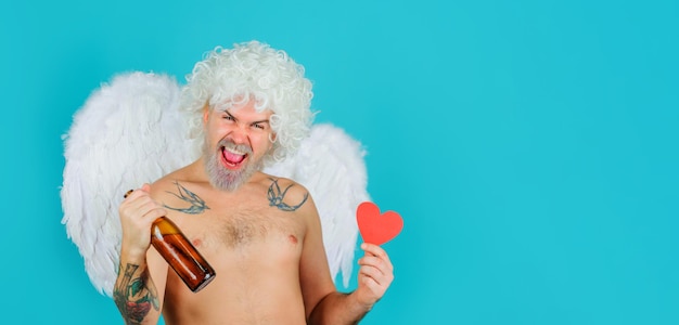 Cupido ubriaco cattivo di san valentino in ali d'angelo con bottiglia di birra e biglietto di san valentino con cuore di carta