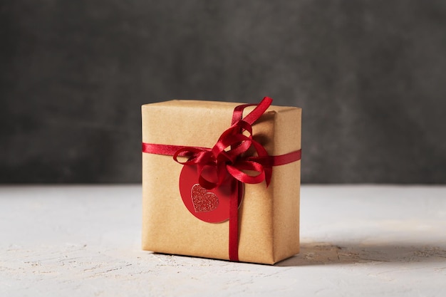 Photo valentines day present gift box wrapped in brown craft paper with red ribbon and red tag, side view