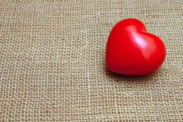 Valentines day red heart on a brown burlap background. Flat lay, space for text.