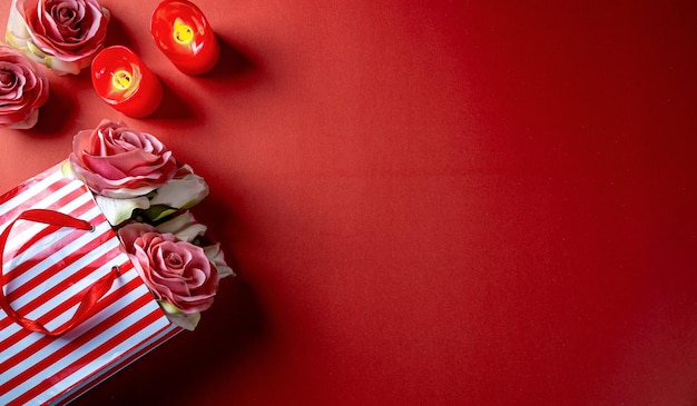 Tema rosso di san valentino con fiore, pacchetto regalo di fiori e candele nell'angolo.