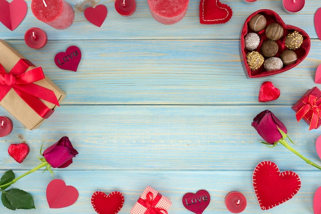 Valentines day romantic decoration with roses and chocolate on a blue wooden table.