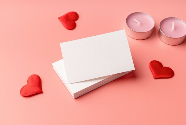 Valentines Day. Stack of visit cards on pink background with hearts and candles for mock up design