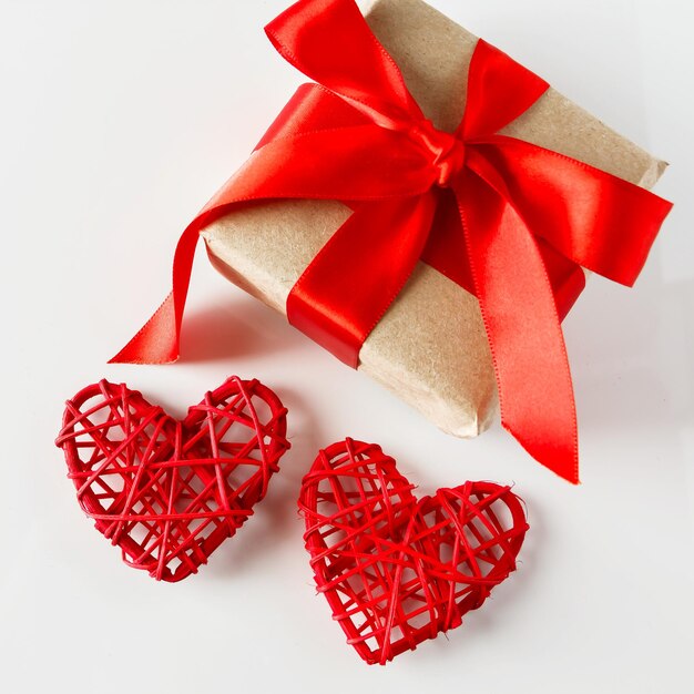 Photo valentines day surprise with red ribbon and 2 hearts close-up on a white background