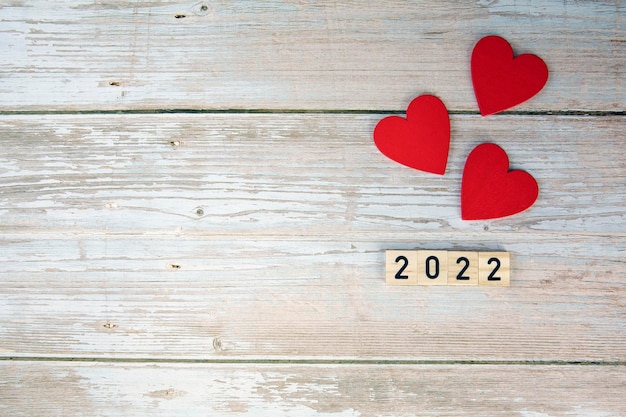 San valentino simbolo sfondo 2022 anno e cuori rossi su fondo in legno design romantico