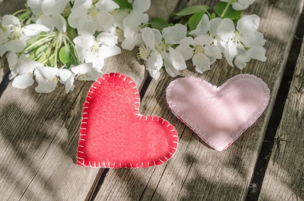 Photo valentines day, two hearts on wooden table with apple tree flowers with sunbeams