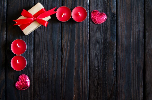 赤いハート、ギフト、キャンドルでバレンタインデーの木製の背景。バレンタインデーのギフト。黒の木製の背景