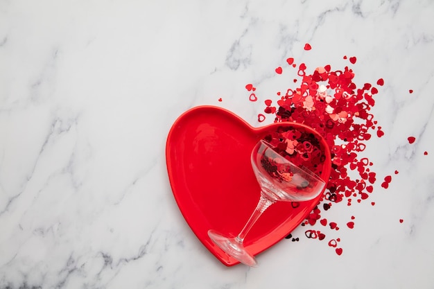 Valentines dinner background red heart plate with champagne glass and confetti