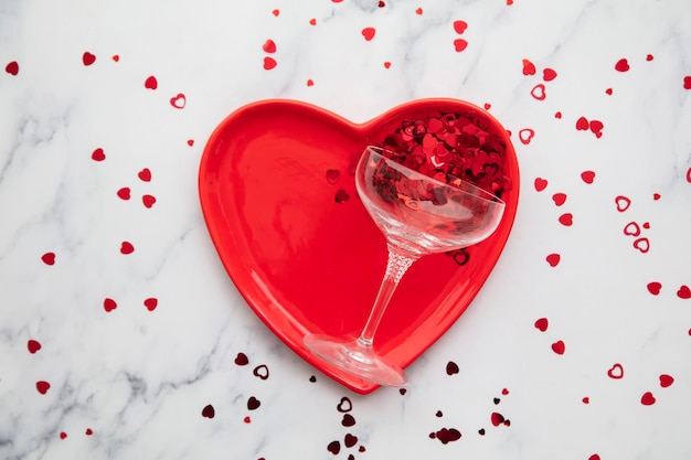 Valentines dinner background red heart plate with champagne glass and confetti