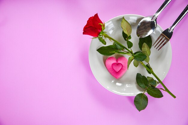 Valentines dinner romantic love food and love cooking fork spoon pink heart and roses on plate with pink texture background