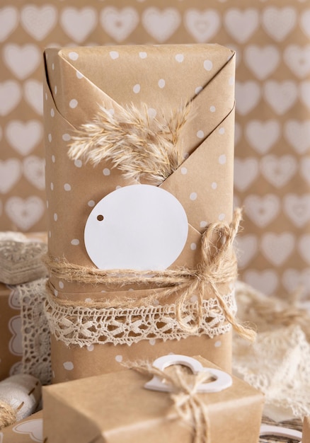 Valentines kraftpapier verpakt cadeau met ronde cadeau-tag, harten en pampagras close-up. lente tafereel met blanco label. rustiek, cottage chic of bohemien mockup, kopieer ruimte