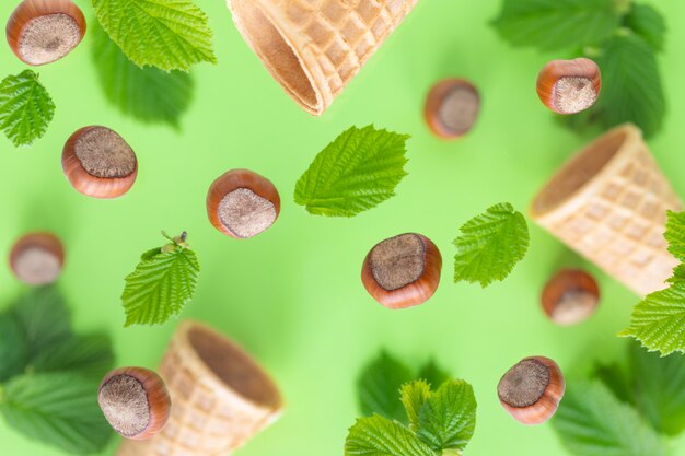 Vallende hazelnoten met groene bladeren en wafelbekers voor ijs