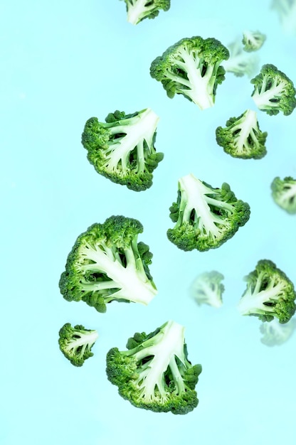 Vallende stijgende groene broccoli plakjes op een blauwe achtergrond