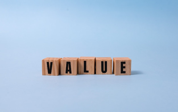 VALUE word written on wood block on blue.