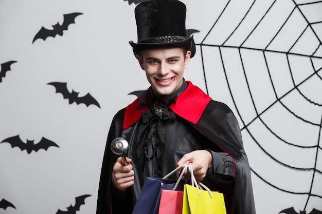 Vampire Halloween Concept Happy handsome caucasian Vampire holding colorful shopping bag