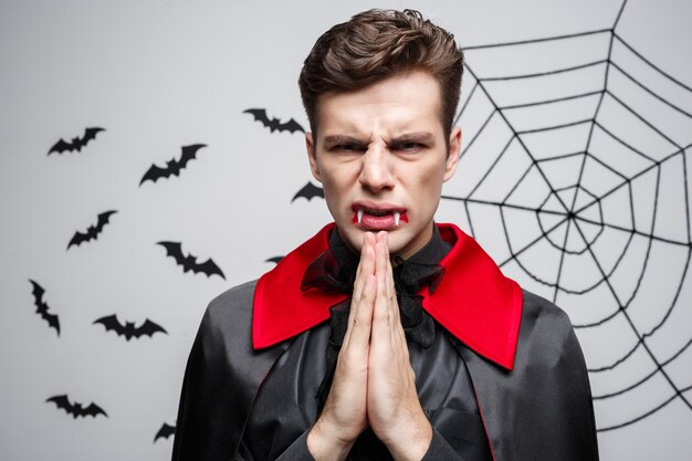 Vampire Halloween Concept - Portrait of handsome caucasian in Vampire halloween costume praying.