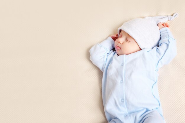 Van bovenaf geschoten van een mooie baby die thuis op een zacht bed slaapt, close-up