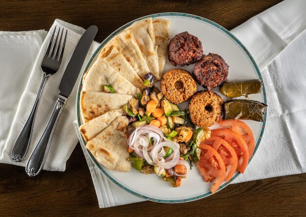 Van bovenaf uitzicht op grieks vegetarisch monster met falafel pita en dolmades meeneemmaaltijden thuis verguld met servet