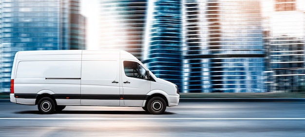 Photo van driving on a city road at sunset in front of a modern cityscape