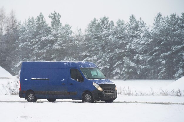 写真 雪の中のバン運転 雪のある冬の日に物流 冬の降雪による貨物配達の遅延 商用貨物バン側景色