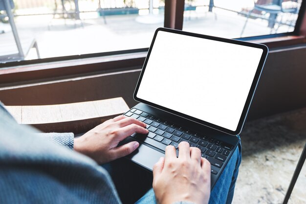 van een vrouw die op toetsenbord van de tablet gebruikt en typt met een leeg wit bureaubladscherm als computer-pc