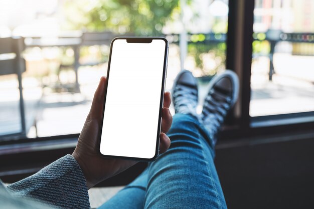 van een vrouw met mobiele telefoon met lege witte desktop-scherm zittend in café