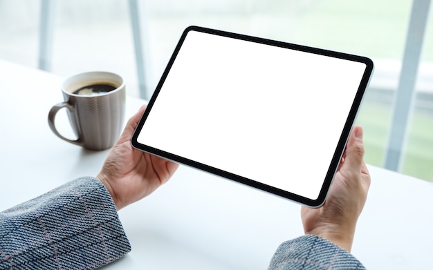 van een vrouw met zwarte tablet-pc met leeg wit scherm met koffiekopje op tafel