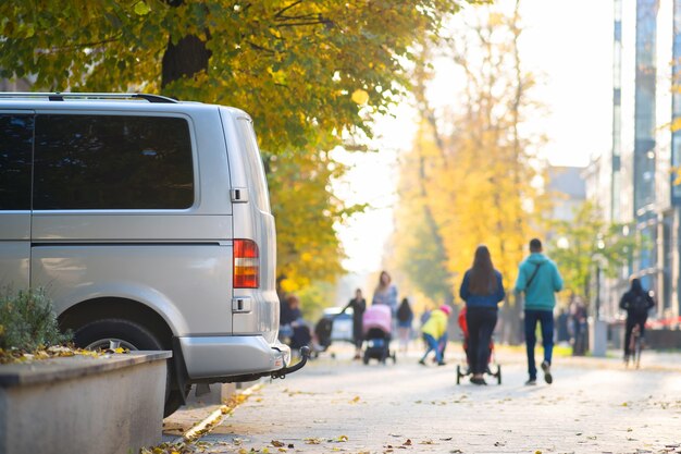 Van geparkeerd aan de straatkant van een stad op een heldere herfstdag met wazige mensen die in het voetgangersgebied lopen.