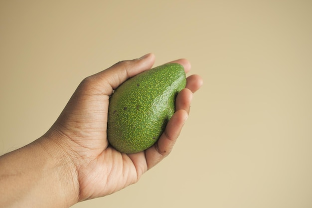 van het vasthouden van een avocado tegen een muur