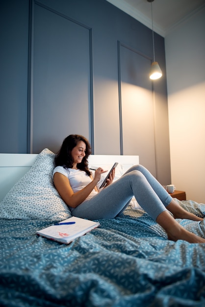 Van middelbare leeftijd lachende ondernemers vrouw laat thuis werken terwijl liggend op het bed.