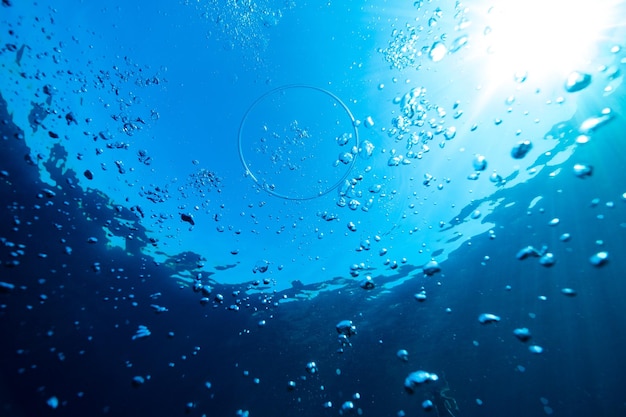 Van onderen van vortex ring en bubbels in helder transparant zeewater tegen wolkenloze blauwe lucht