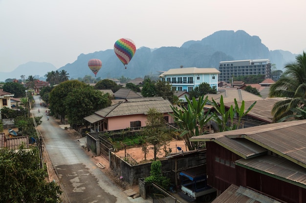 VANG VIENG LAOS Hot air balloons over the street with local houses and a road Mis