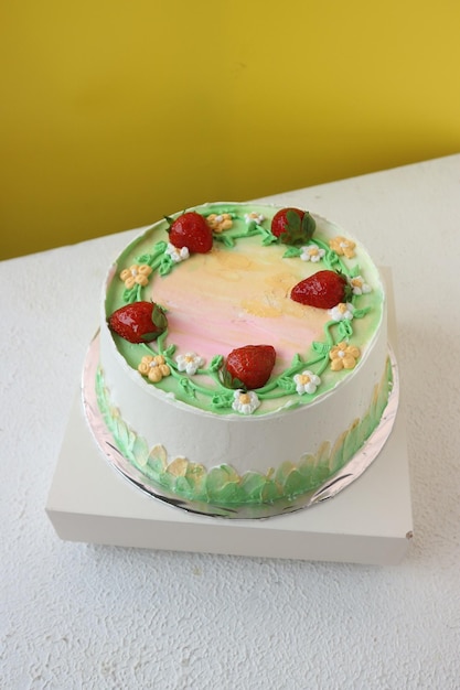 Foto torta alla vaniglia con decorazioni verdi e rosa e fragole a fette