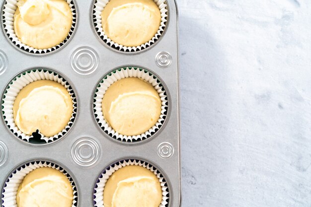 Vanilla cupcake batter in foil cupcake liners to bake Mardi Gras vanilla cupcakes.