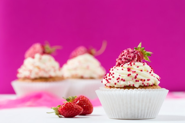 Vanilla cupcakes decorated strawberries on pink 