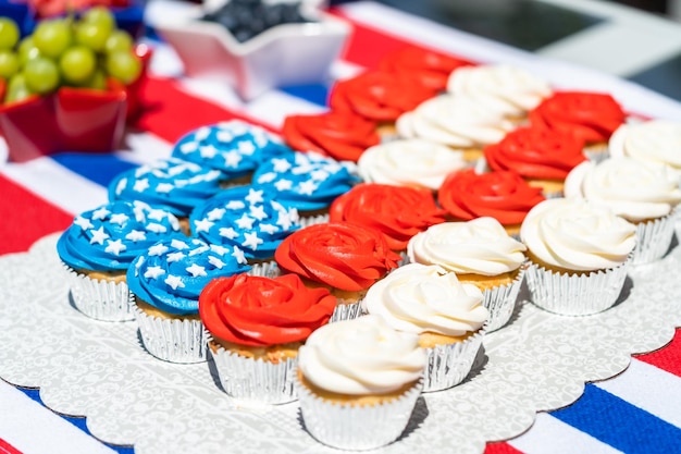 Vanilla cupcakes with red, blue, and white icing shaped in an\
american flag.