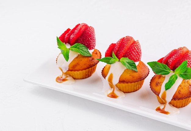 Vanilla cupcakes with strawberry on white plate