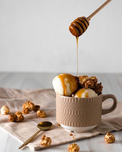 Vanilla ice cream in balls in a mug Decorated with popcorn Honey is poured on the ice cream