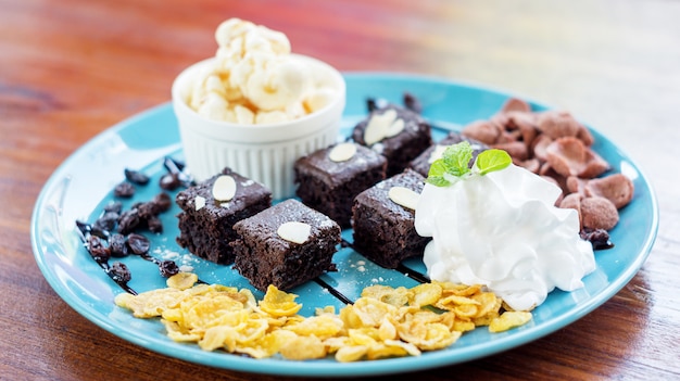 Gelato alla vaniglia e brownies su un piatto blu.