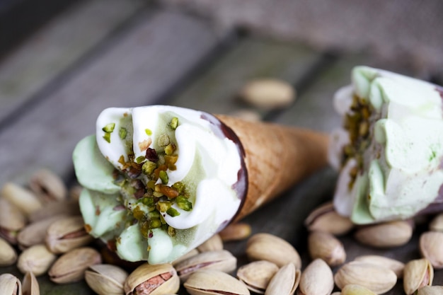 Vanilla ice cream cone with pistachio nuts. Pistachio nuts in the background.Close up