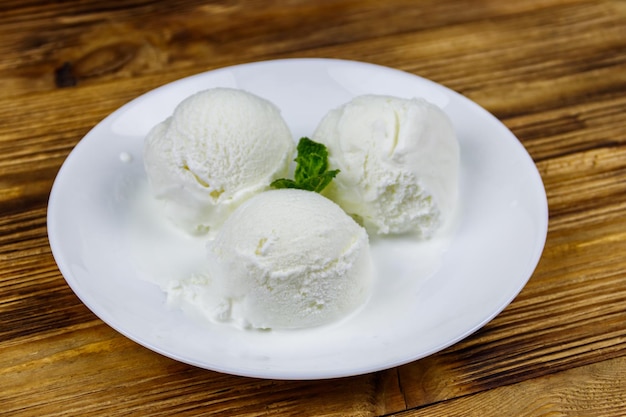 Ванильное мороженое в белой тарелке на деревянном столе