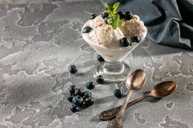 Foto gelato alla vaniglia con i mirtilli su un fondo concreto grigio.