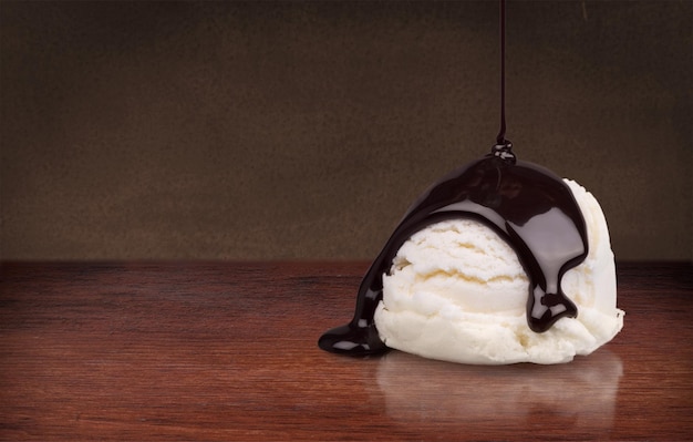 Vanilla ice cream with chocolate sauce on dark background