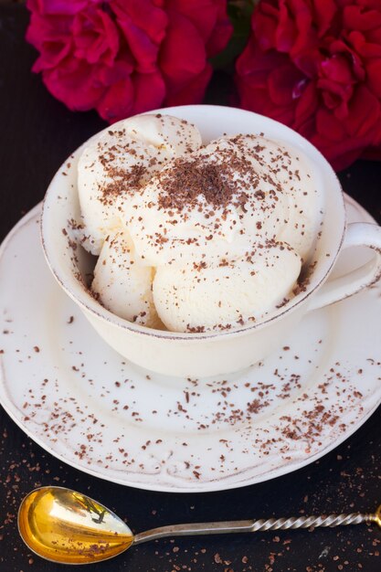 Vanilla ice cream with chocolate  in white cup with golden spoon