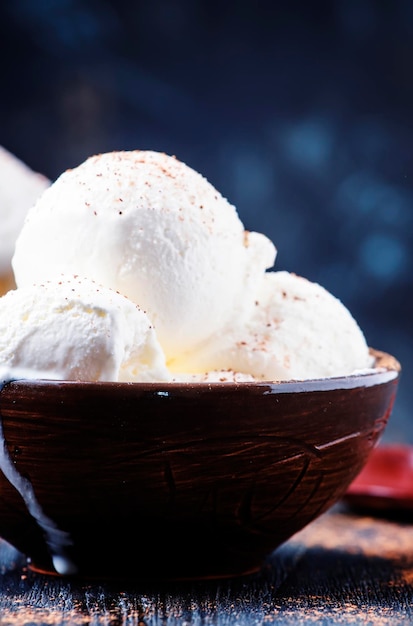 Vanilla ice cream with ground cocoa in brown bowls dark background selective focus