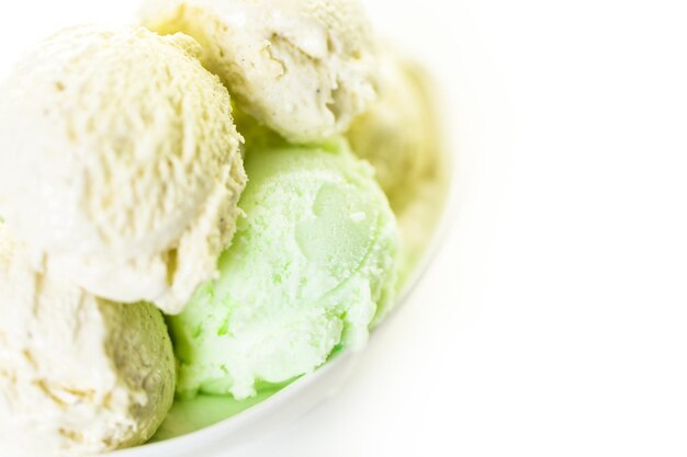 Vanilla and lime ice cream scoops in a white cup.