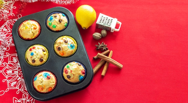 Vanilla muffins with chocolate candy, spicy and lemon. Christmas bakery concept. Top view. Red burlap background. Copy space.