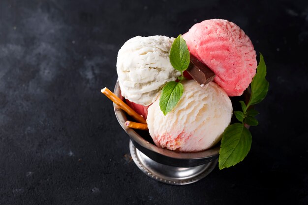 Vanilla and pink ice cream in a bowl with frozen berries and waffle cone