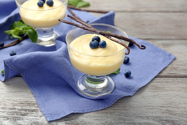 Vanilla pudding served in dessert bowls with blueberries on wooden table