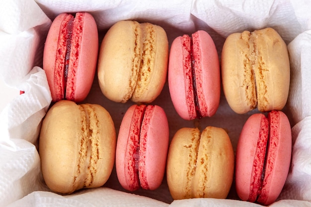 Vanilla and strawberry macaroons in a box on white paper sweets