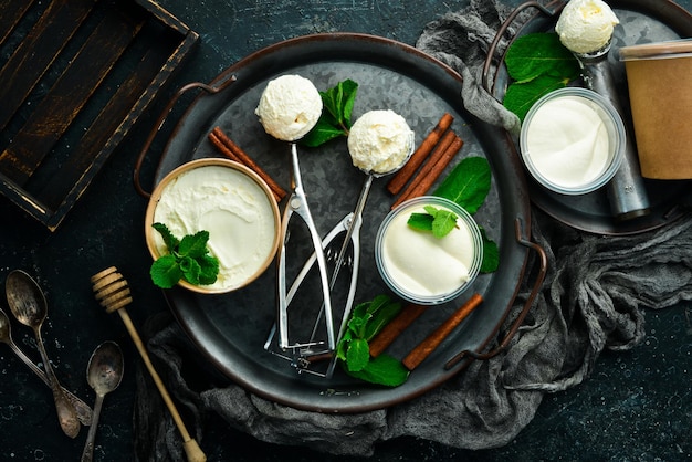 Vanilla sweet ice cream with mint. Ice cream spoon. On a black stone background, top view.